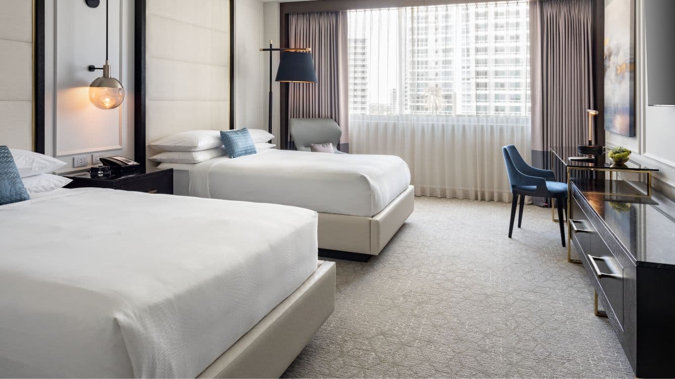 A standard guest room at the JW Marriott Miami — a made bed, a work desk and floor-to-ceiling windows over the city.